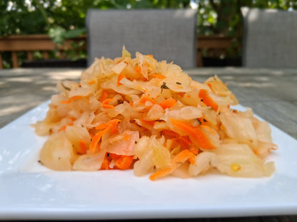Cabbage and carrot salad on a white plate with a blurred outdoor background